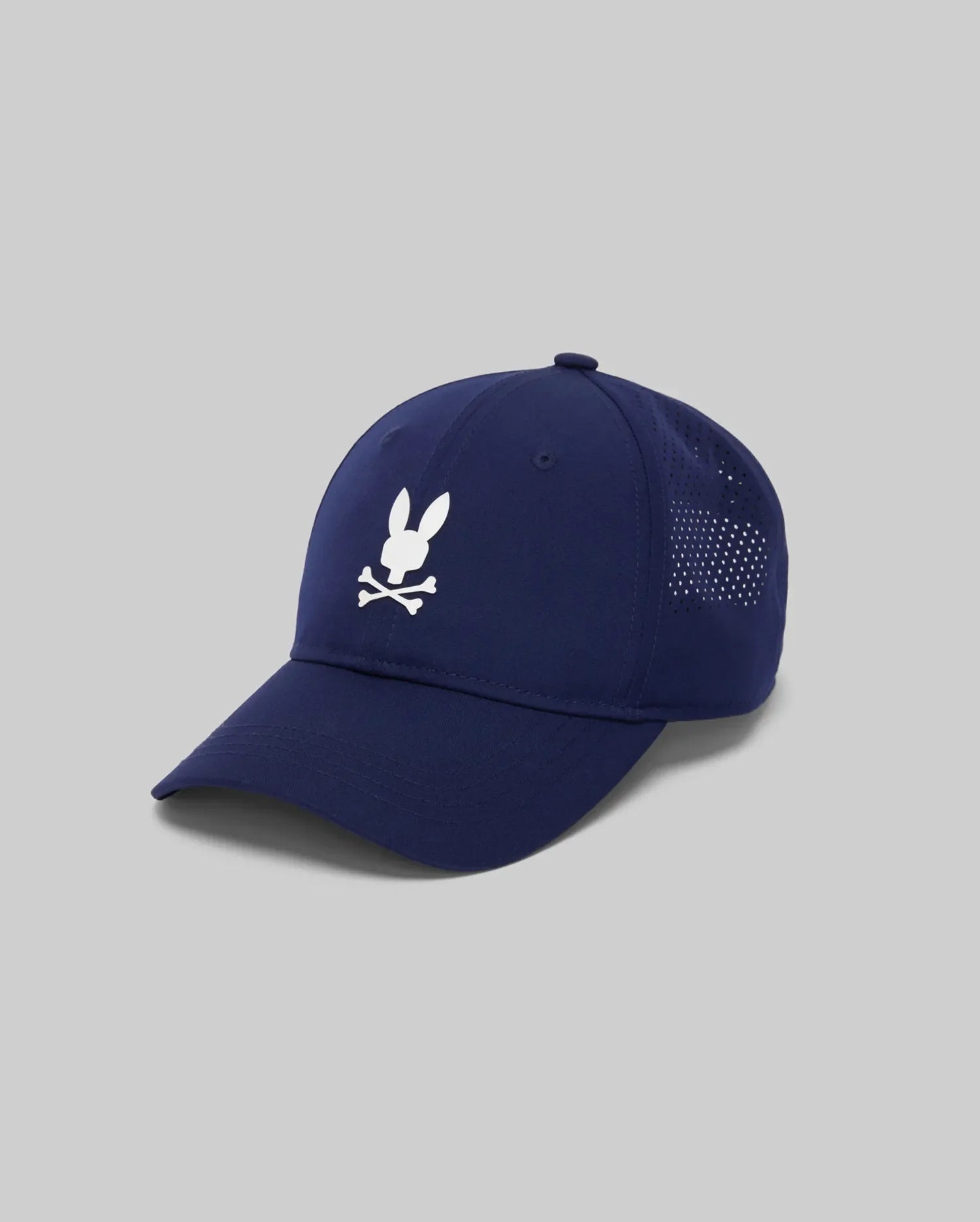 The Psycho Bunny MENS FORREST SPORT CAP (MO1500046) is a navy blue athletic cap with a white bunny head and crossbones logo, mesh ventilation panels, sweat-wicking interior, adjustable strap, shown on a light gray background.