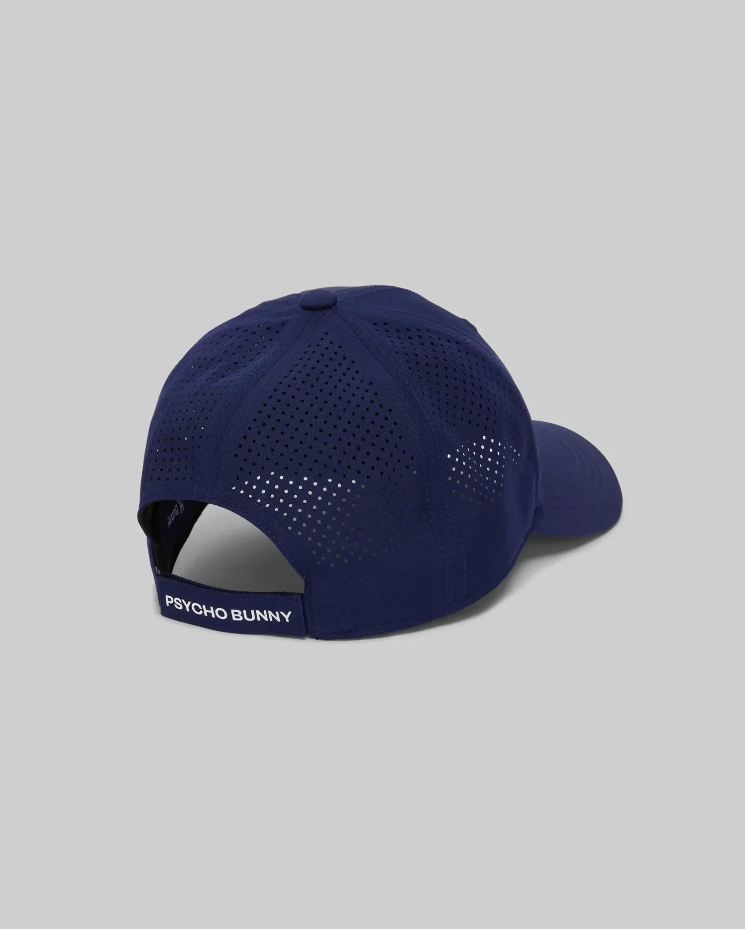 The Psycho Bunny MENS FORREST SPORT CAP (MO1500046) is a navy blue baseball cap with sweat-wicking perforated panels, an adjustable strap displaying "PSYCHO BUNNY," shown against a gray background.