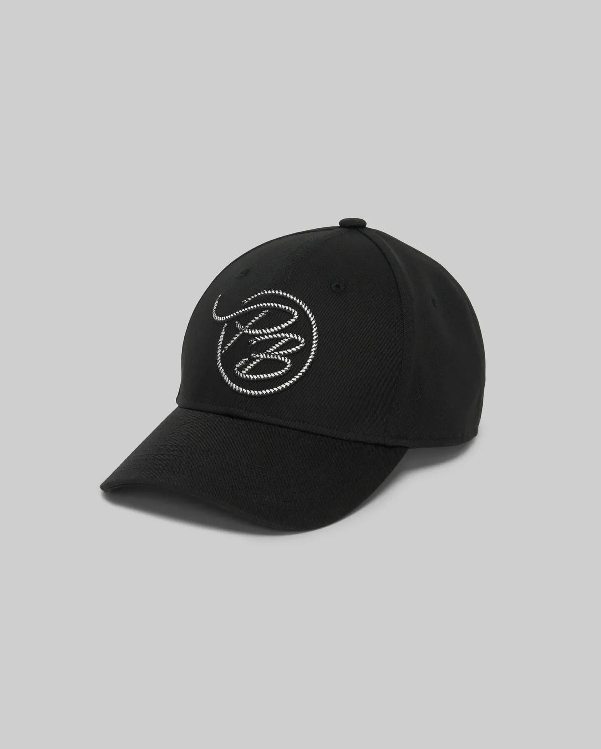 The Psycho Bunny MENS CYRUS PB BASEBALL CAP - MO1500047 is a black baseball cap with a white circular rope-style abstract embroidered logo on the front, shown against a plain grey background.