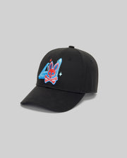 The Psycho Bunny MENS MONTREAL BASEBALL CAP (MO1500048) is made from 100% cotton and showcases a vibrant embroidered red rabbit skull with blue ears and crossbones over blue and white geometric shapes on the front.
