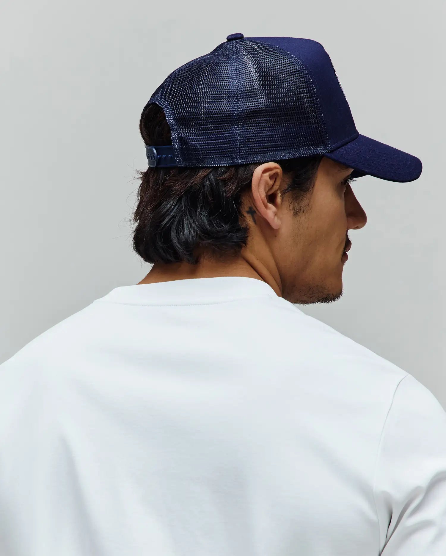 Navy Mens Toby Trucker Cap, a Psycho Bunny essential, featuring a structured front panel and breathable mesh back, paired with a soft white classic fit jersey crew neck t-shirt.