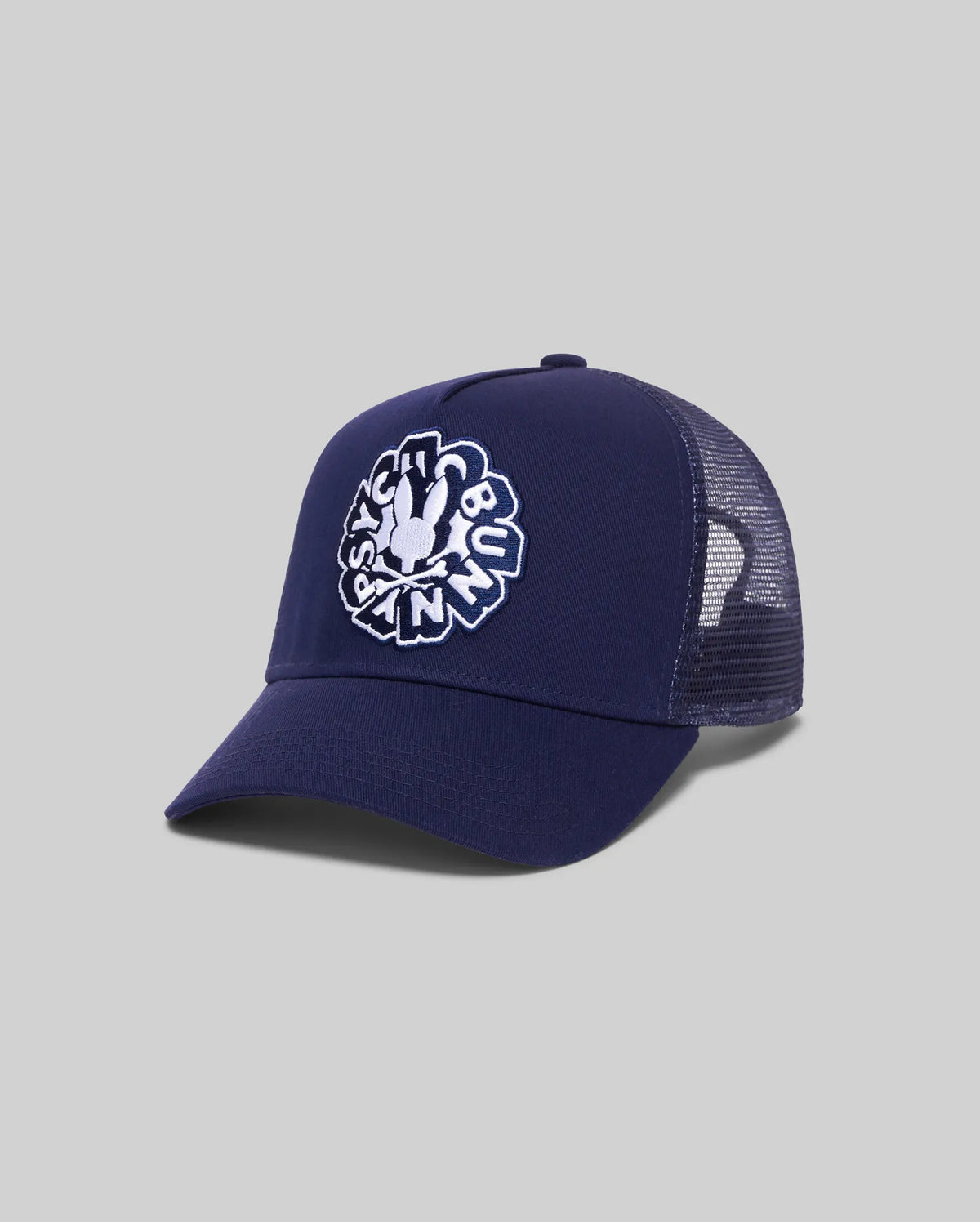Mens Toby Trucker Cap in navy, featuring a solid front panel and breathable mesh back. A large, centered white embroidered Psycho Bunny skull logo with text adorns the front.