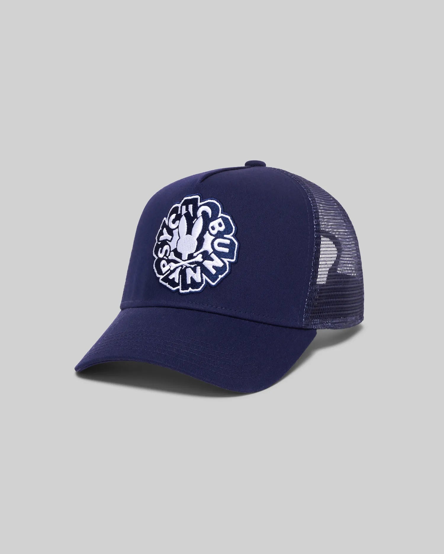 Mens Toby Trucker Cap in navy, featuring a solid front panel and breathable mesh back. A large, centered white embroidered Psycho Bunny skull logo with text adorns the front.