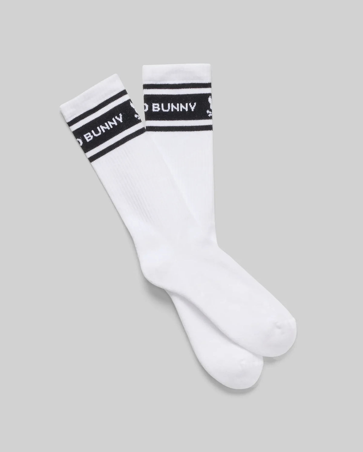 The Psycho Bunny MENS 3 PACK SPORT SOCK - MO2200006 features white Pima cotton crew socks with black bands, white text, and a small bunny logo. Inspired by vintage motifs, they're displayed flat on a light gray background.
