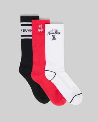 The Psycho Bunny MENS 3 PACK SPORT SOCK (MO2200008) features three pairs of soft Pima cotton crew socks in black, red, and white with iconic bunny logos, shown side by side on a grey background.