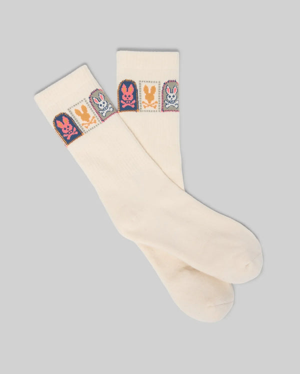 The Psycho Bunny MENS SUNDEW GRAPHIC SPORT SOCK (MO2200020) features cream-colored Pima cotton with colorful bunny graphics and small cartoon bunnies near the top, displayed on a light gray background.