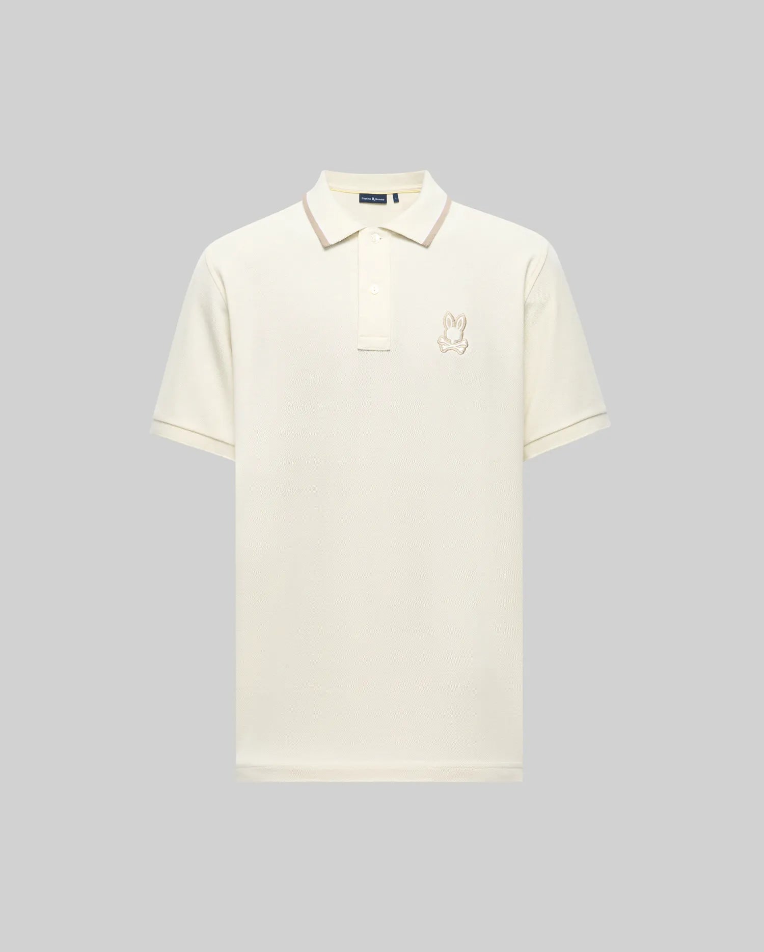 The Psycho Bunny MENS FENLEY PIQUE POLO (MT0100009) is an off-white Pima cotton shirt with short sleeves, a collar, Mother-of-Pearl buttons, and a small bunny logo embroidered on the left chest, shown on a light gray background.