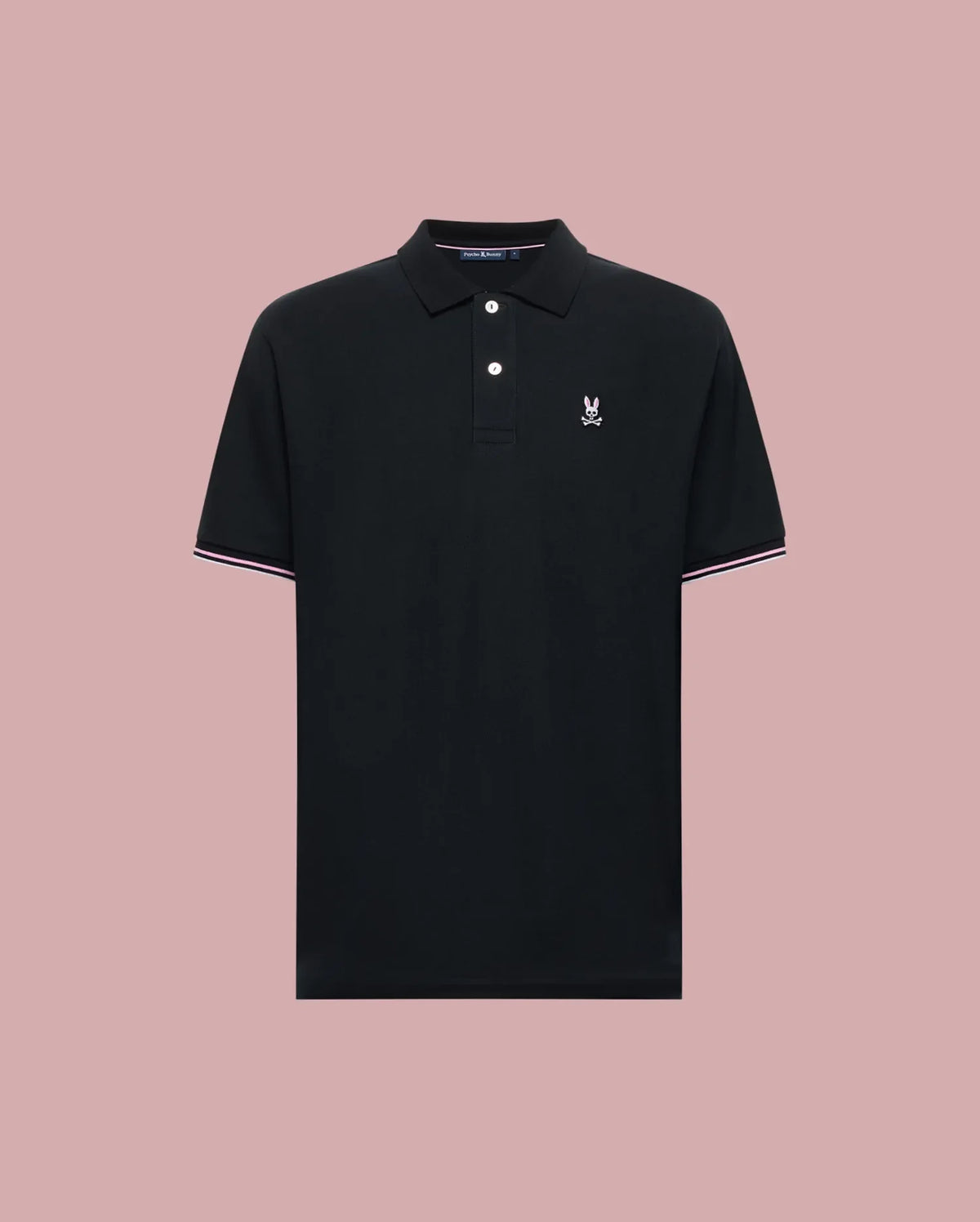 The Psycho Bunny MENS ARCHIVE CLASSIC BUNNY PIQUE POLO (MT0100010) is a black Pima cotton short-sleeve polo with a collar, two buttons, white and pink trim accents, and a white embroidered logo on the chest. Displayed on light pink.