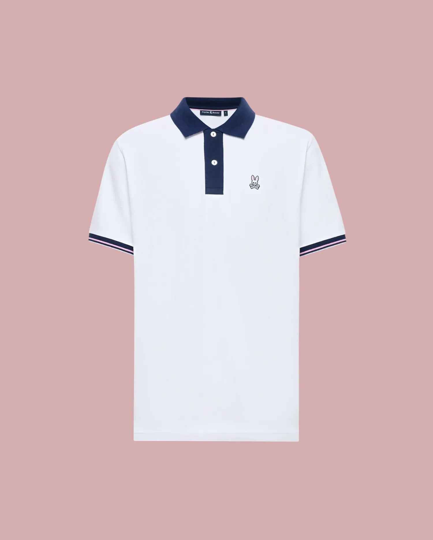The Psycho Bunny MENS ARCHIVE CLASSIC BUNNY PIQUE POLO (MT0100010) is a white Pima cotton short-sleeve polo with a navy collar, button placket, sleeve trim, and an embroidered Bunny logo on the chest, shown on a pink background.