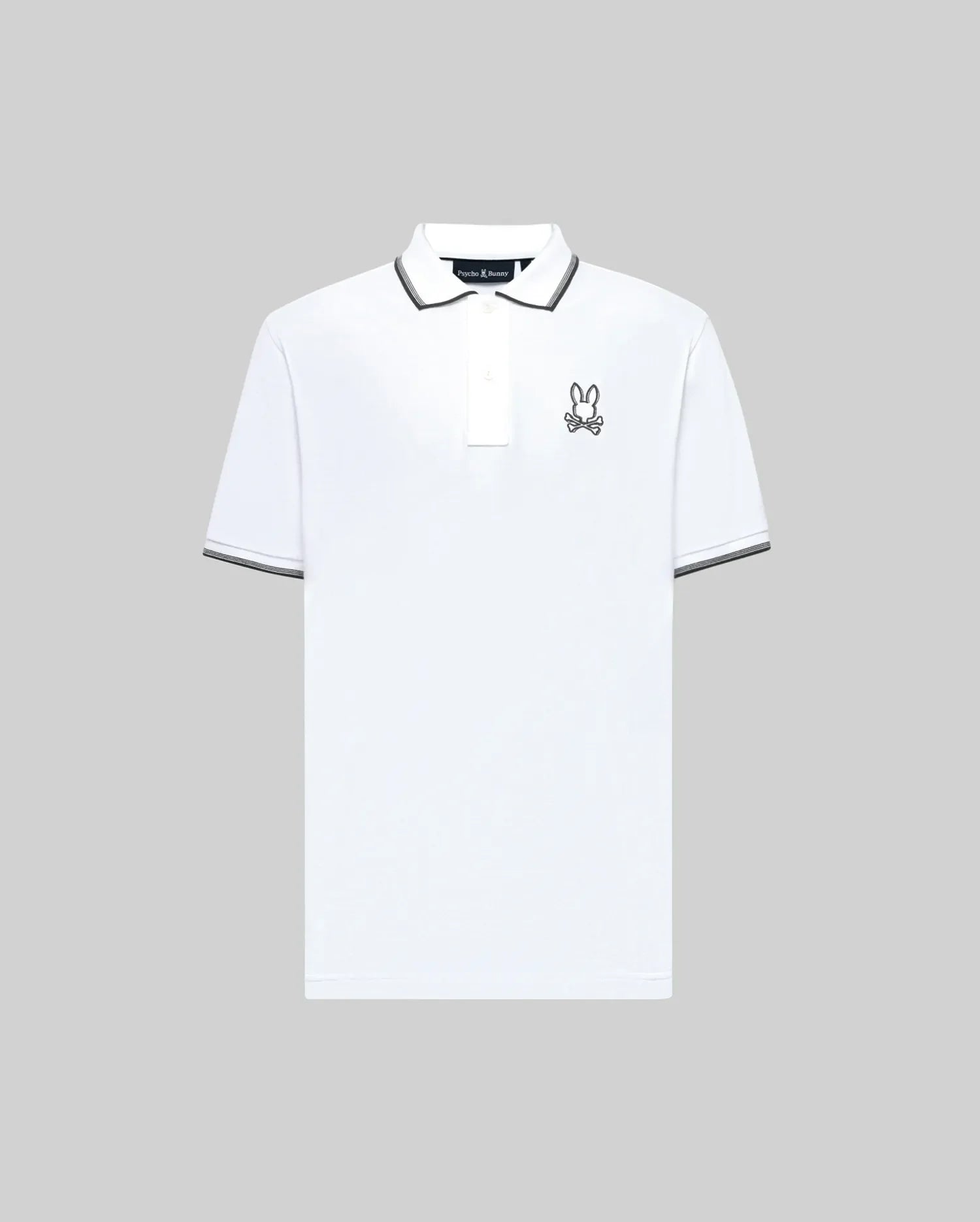 The Psycho Bunny MENS JUDE PIQUE POLO - MT0100012 is a white Pima cotton shirt with a black and white collar and sleeve trim, plus an embroidered Bunny logo on the left chest, shown against a plain gray background.