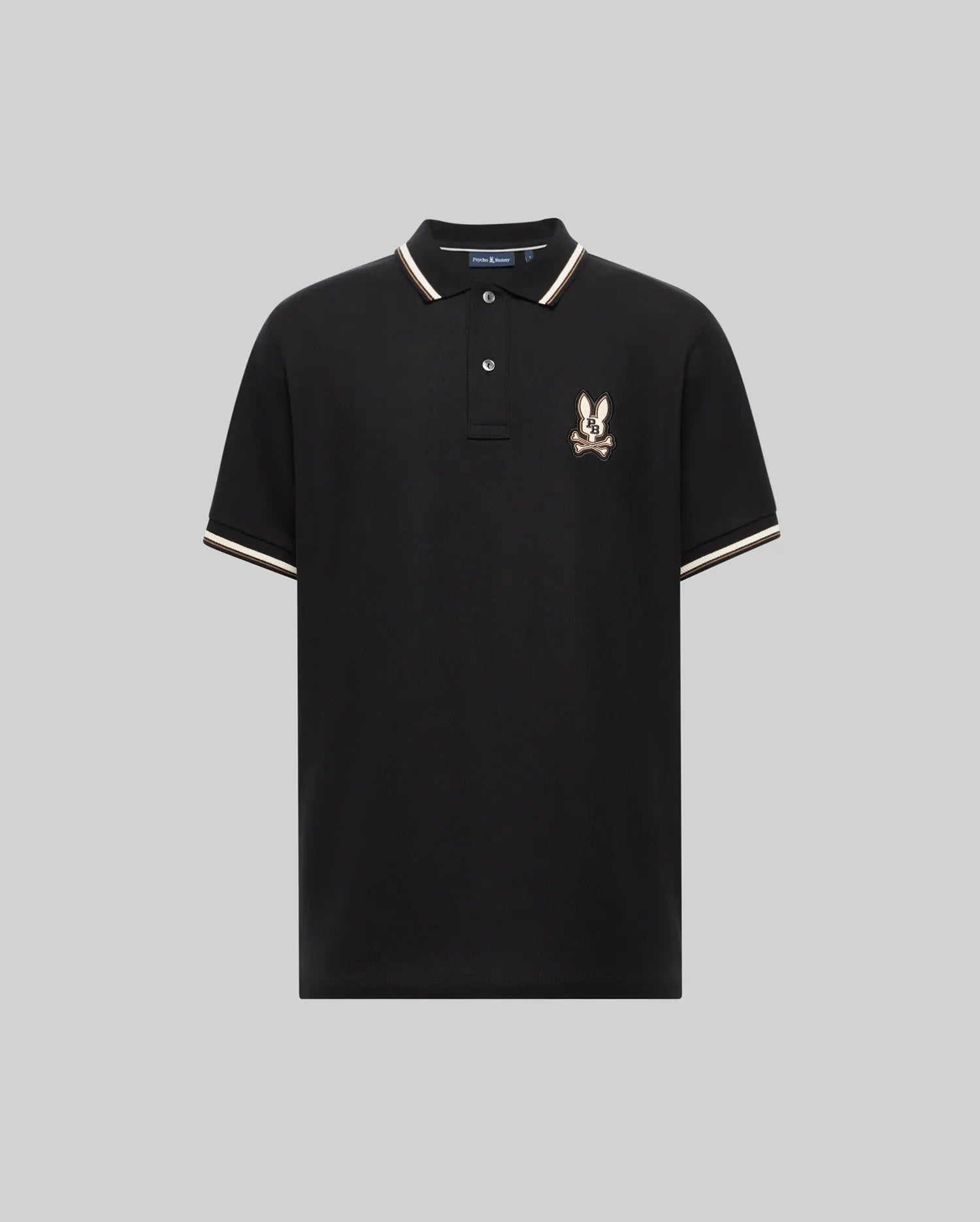 The Psycho Bunny MENS WADE PIQUE POLO (MT0100044) is a black Pima cotton polo for men, featuring white and beige colorblock trim on the collar and sleeves, plus an embroidered eagle crest logo on the left chest. Displayed on a plain gray background.