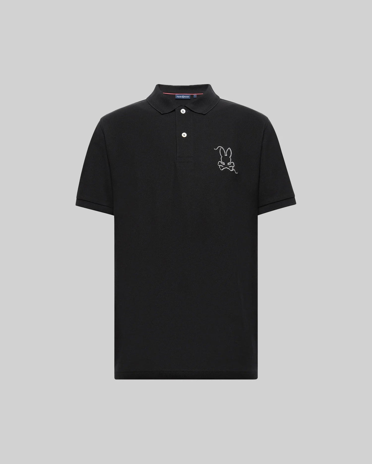The Psycho Bunny MENS CYRUS PIQUE POLO - MT0100056 is a black Pima cotton polo with short sleeves, a three-button collar, and a white embroidered cartoon bunny outline on the left chest, shown on a plain light gray background.