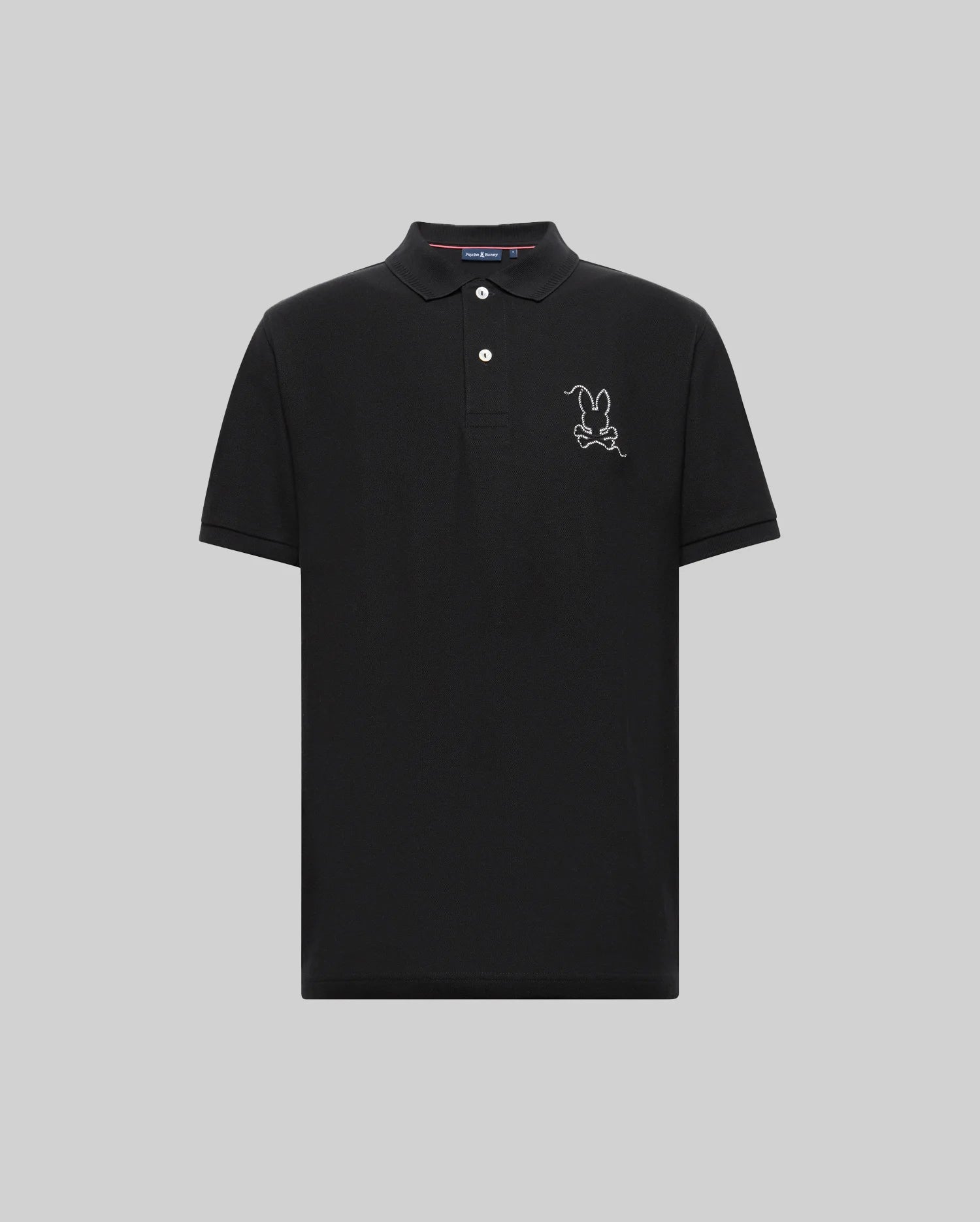 The Psycho Bunny MENS CYRUS PIQUE POLO - MT0100056 is a black Pima cotton polo with short sleeves, a three-button collar, and a white embroidered cartoon bunny outline on the left chest, shown on a plain light gray background.