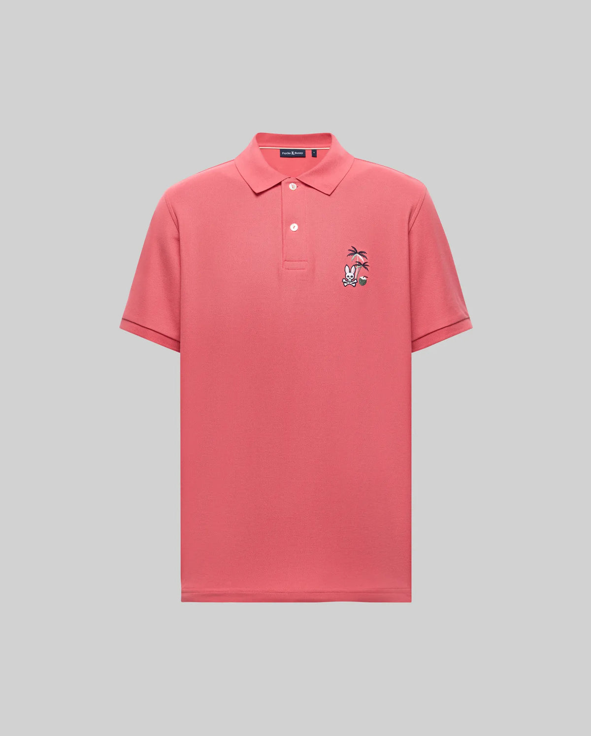 The Psycho Bunny MENS SONNY PIQUE POLO - MT0100094 is a plain pink short-sleeve Pima cotton shirt with a collar, three buttons, and a charming cartoon character chest embroidery. The background is light gray.