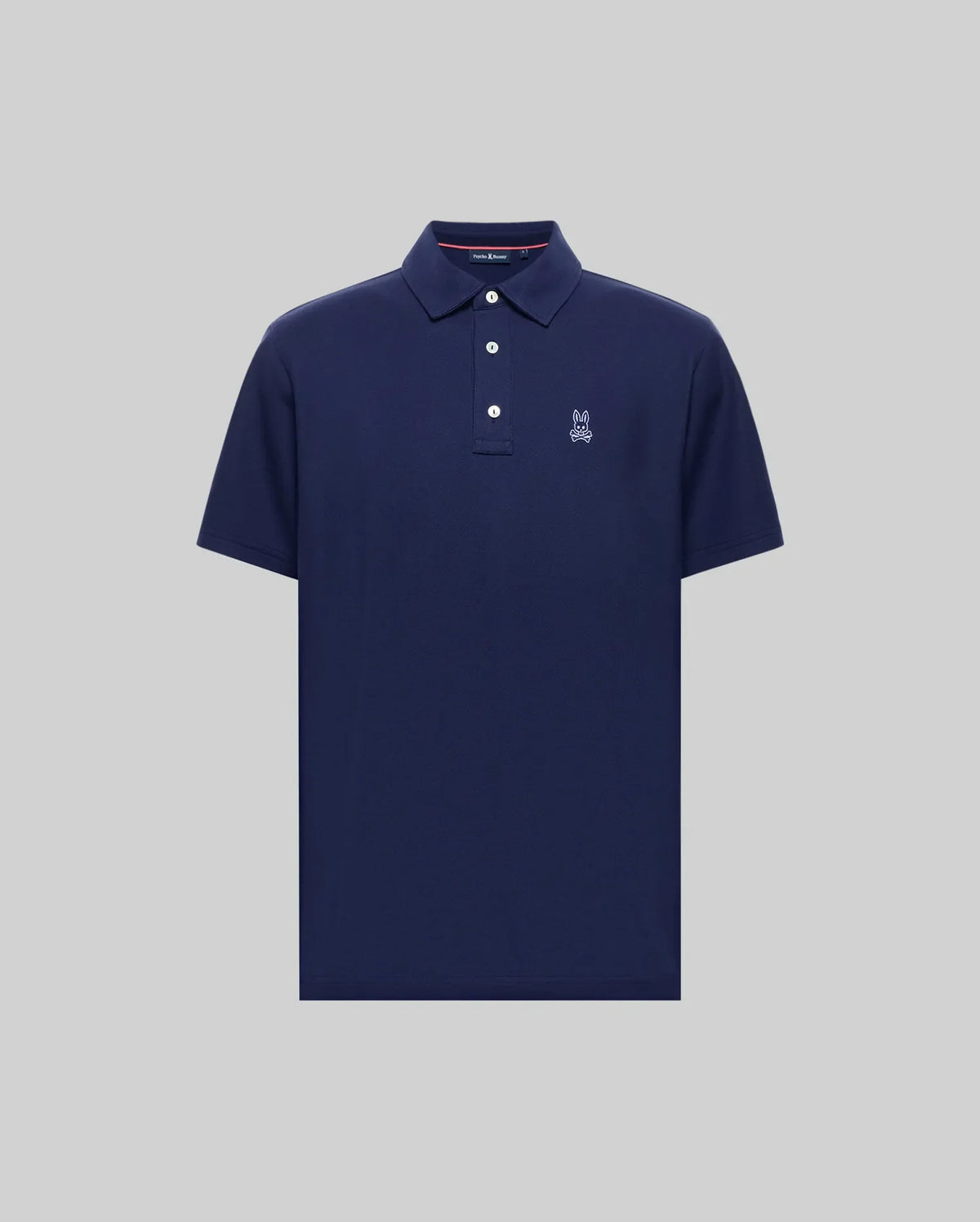 The Psycho Bunny MENS PHOENIX FASHION POLO (MT0100096) is a navy blue, short-sleeve Pima cotton shirt with a collar, three buttons, and a small white embroidered logo on the left chest, shown on a plain grey background.