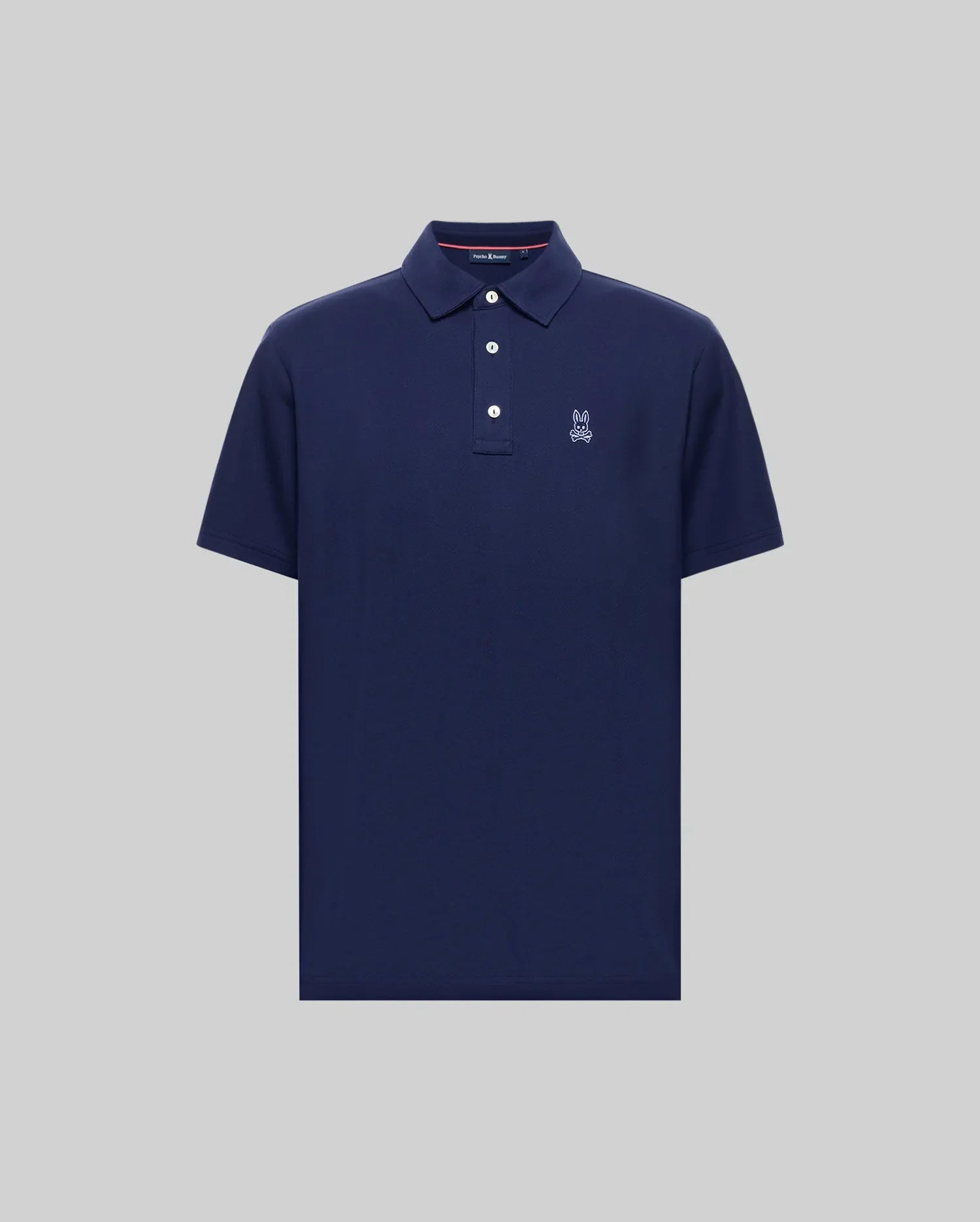The Psycho Bunny MENS PHOENIX FASHION POLO (MT0100096) is a navy blue, short-sleeve Pima cotton shirt with a collar, three buttons, and a small white embroidered logo on the left chest, shown on a plain grey background.