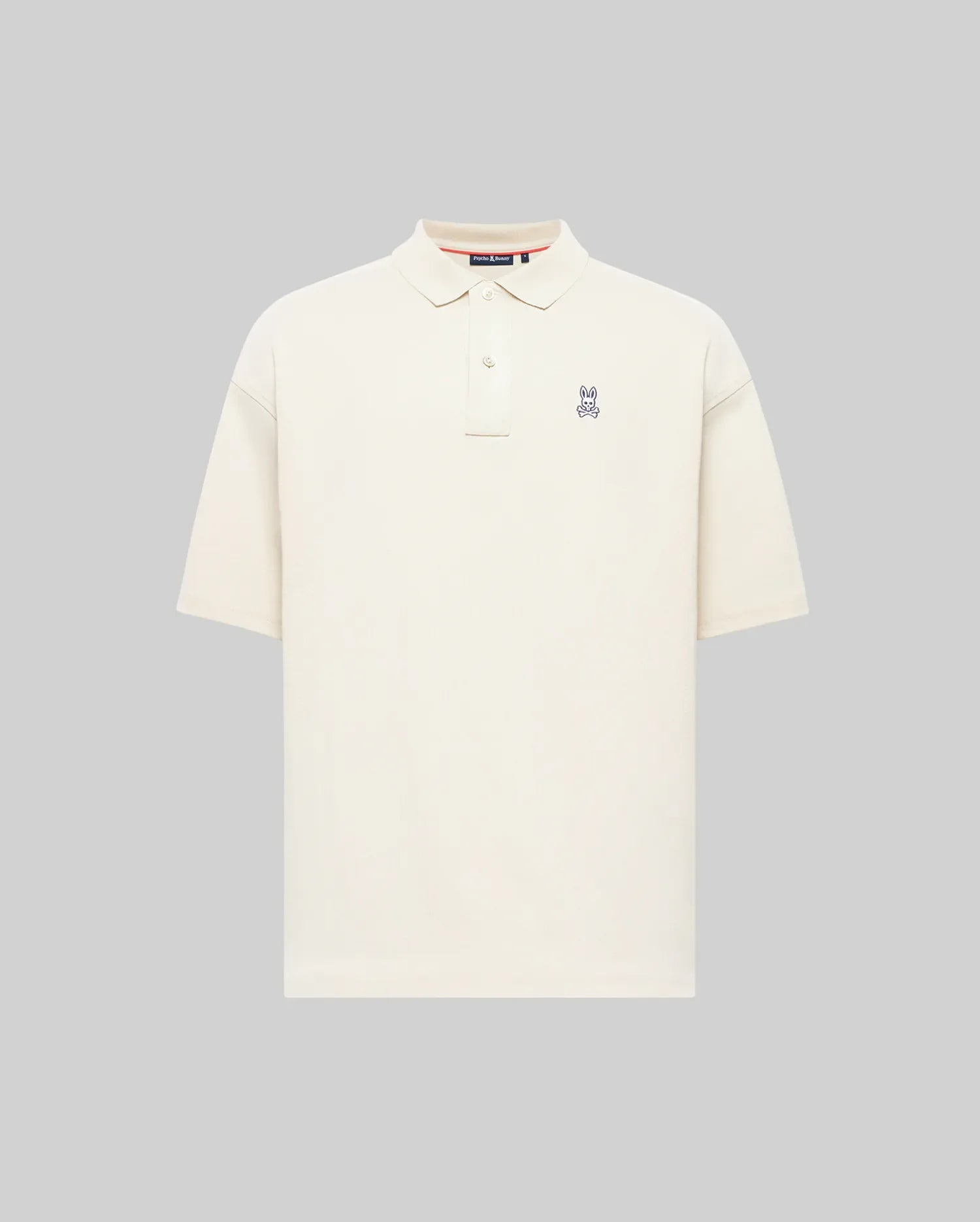 The Psycho Bunny MENS HENRY OVERSIZED FIT POLO (MT0100104) is a soft Pima cotton jersey shirt in plain off-white, with short sleeves, a collar, button placket, and small embroidered bunny logo on the chest. Displayed on a light gray background.