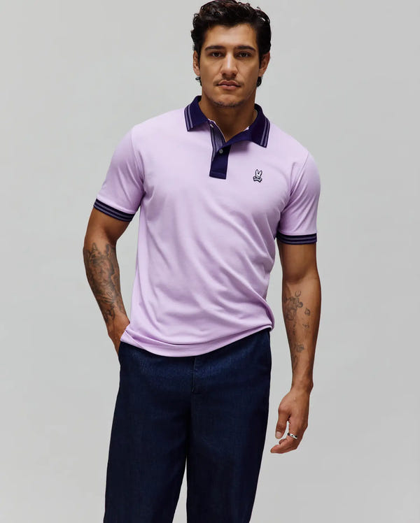 Mens Kenyon Pique Polo in lavender pique with a navy blue collar and cuffs featuring white stripes, a two-button placket, and a small embroidered Psycho Bunny skull logo on the left chest.
