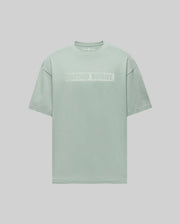 The Psycho Bunny MENS ZAYN OVERSIZED GRAPHIC TEE (MT0200004) is a pastel green heavyweight jersey short-sleeve t-shirt featuring bold white "PSYCHO BUNNY" lettering on the chest, shown against a light gray background.