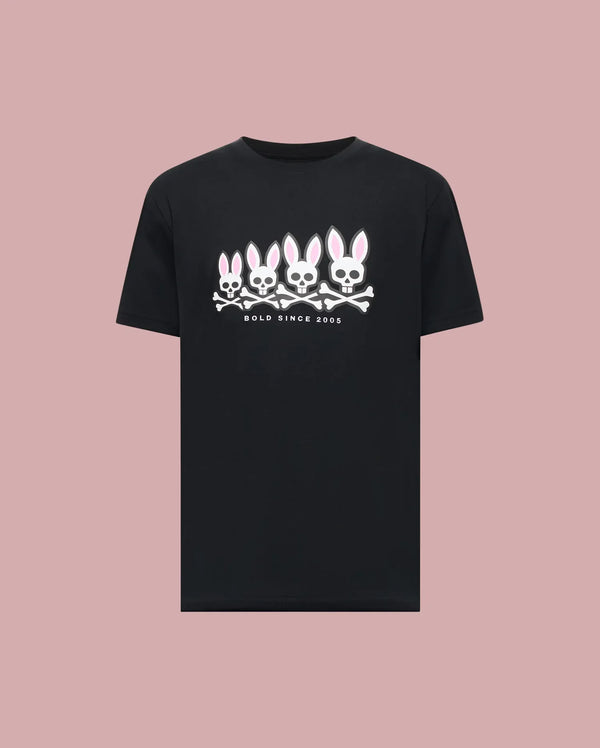 The Psycho Bunny MENS ARCHIVE GRADIANT BUNNY GRAPHIC TEE (MT0200029) showcases four iconic white and pink Bunny skull and crossbones with "BOLD SINCE 2005" text, set against a plain light pink background.