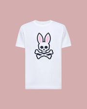 The Psycho Bunny MENS ARCHIVE BUNNY GRAPHIC TEE (MT0200031) is a white Pima cotton t-shirt featuring a large skull with bunny ears and crossbones graphic on the front, rib knit crewneck, shown against a muted pink background.