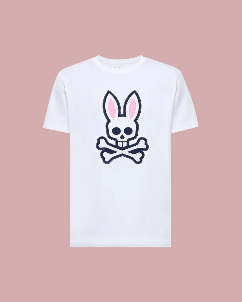 The Psycho Bunny MENS ARCHIVE BUNNY GRAPHIC TEE (MT0200031) is a white Pima cotton t-shirt featuring a large skull with bunny ears and crossbones graphic on the front, rib knit crewneck, shown against a muted pink background.