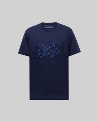 The MENS ELIAS GRAPHIC TEE - MT0200047 by Psycho Bunny is a navy blue Pima cotton short-sleeve shirt, featuring a bold bunny graphic and large "Psycho Bunny" script on the front against a plain light gray background.