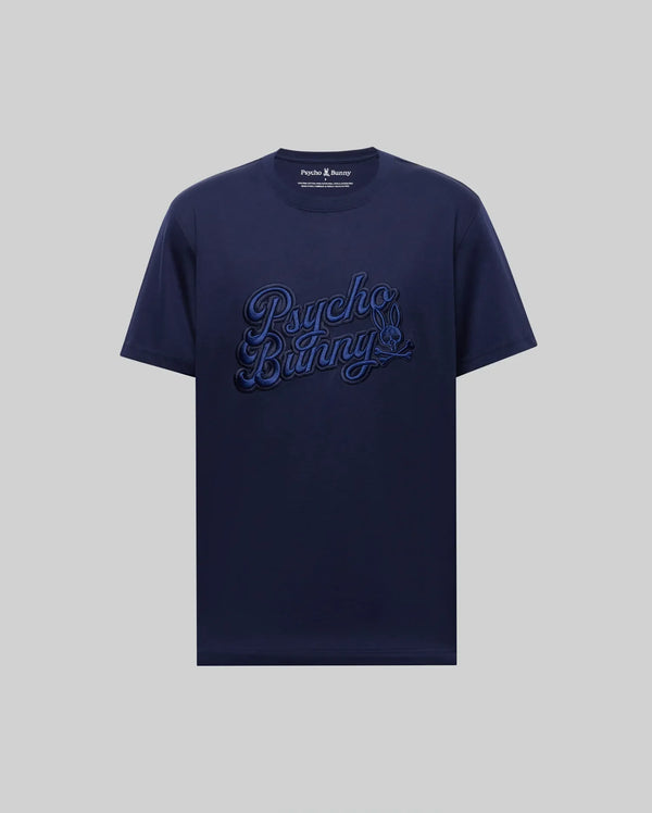 The MENS ELIAS GRAPHIC TEE - MT0200047 by Psycho Bunny is a navy blue Pima cotton short-sleeve shirt, featuring a bold bunny graphic and large "Psycho Bunny" script on the front against a plain light gray background.