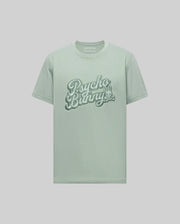 The Psycho Bunny MENS ELIAS GRAPHIC TEE - MT0200047 is a light green Pima cotton shirt with "Psycho Bunny" in bold retro script across the chest and a small crossbones bunny graphic below, shown on a plain background.