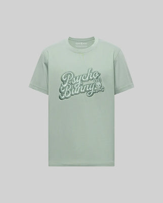 The Psycho Bunny MENS ELIAS GRAPHIC TEE - MT0200047 is a light green Pima cotton shirt with "Psycho Bunny" in bold retro script across the chest and a small crossbones bunny graphic below, shown on a plain background.