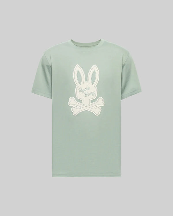 The Psycho Bunny MENS DEREK CENTER GRAPHIC TEE (MT0200048) is a light green Pima cotton short-sleeve shirt with a large white Bunny head and crossed bones graphic, plus "Psycho Bunny" cursive embroidery on the rabbit's face.