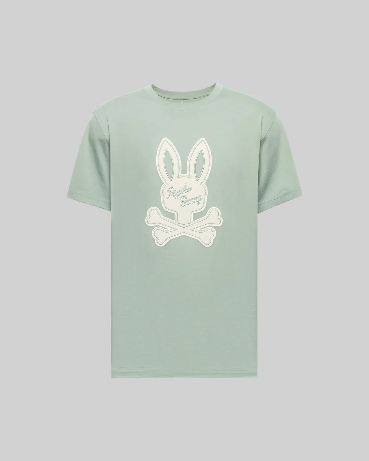 The Psycho Bunny MENS DEREK CENTER GRAPHIC TEE (MT0200048) is a light green Pima cotton short-sleeve shirt with a large white Bunny head and crossed bones graphic, plus "Psycho Bunny" cursive embroidery on the rabbit's face.