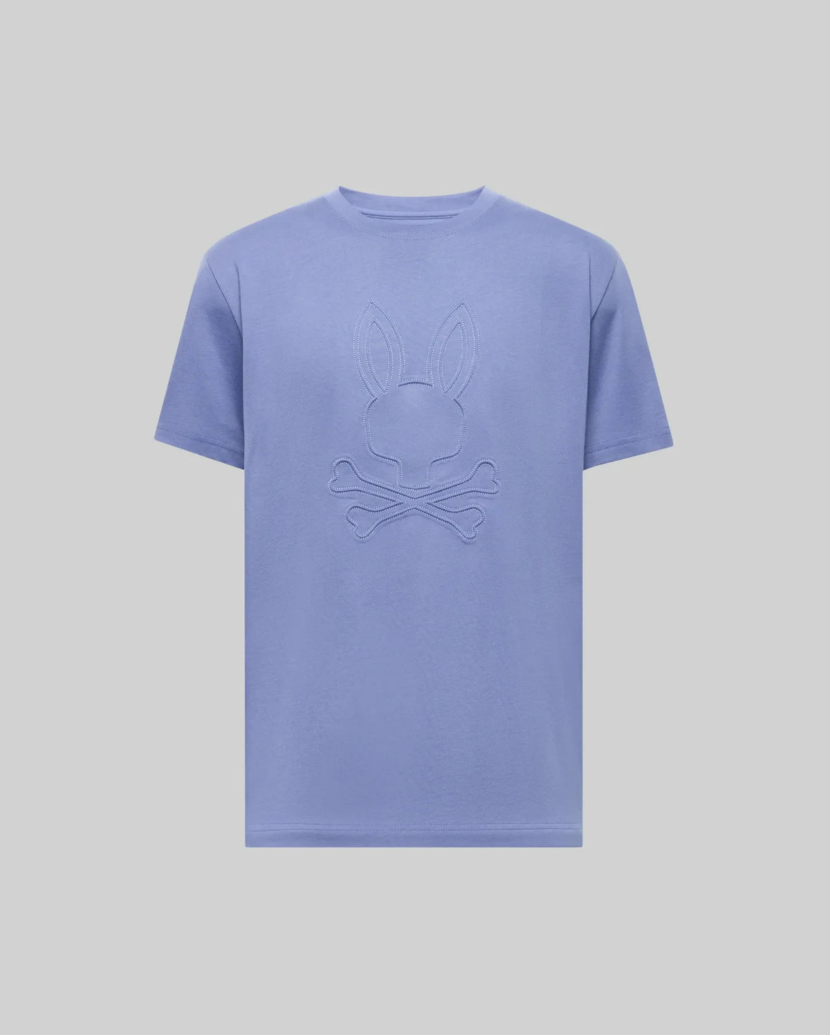 The Psycho Bunny MENS REMY GRAPHIC TEE (MT0200059) is a light purple Pima cotton short-sleeve shirt featuring an embossed bunny logo above crossed bones on the chest, shown on a plain light background.