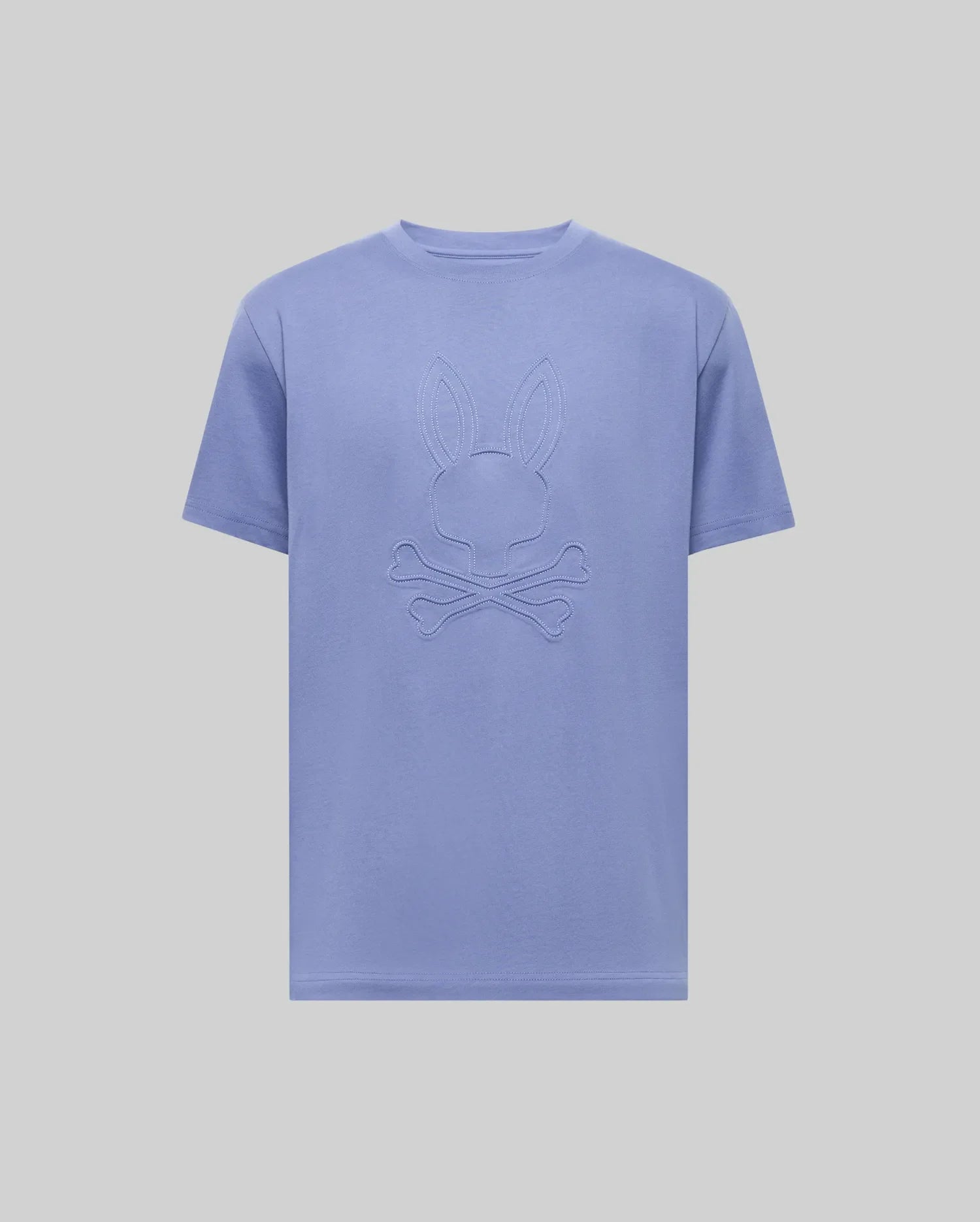 The Psycho Bunny MENS REMY GRAPHIC TEE (MT0200059) is a light purple Pima cotton short-sleeve shirt featuring an embossed bunny logo above crossed bones on the chest, shown on a plain light background.