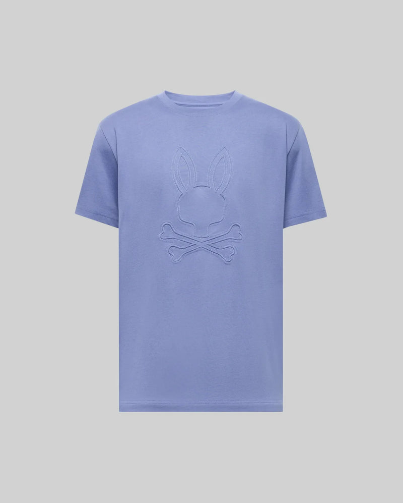 The Psycho Bunny MENS REMY GRAPHIC TEE (MT0200059) is a light purple Pima cotton short-sleeve shirt featuring an embossed bunny logo above crossed bones on the chest, shown on a plain light background.