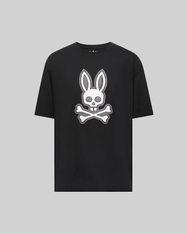 The Psycho Bunny MENS RYDER OVERSIZED FIT TEE (MT0200062) is a black Pima cotton shirt featuring a bold white bunny head with long ears over a skull and crossbones, all set on a plain gray background.