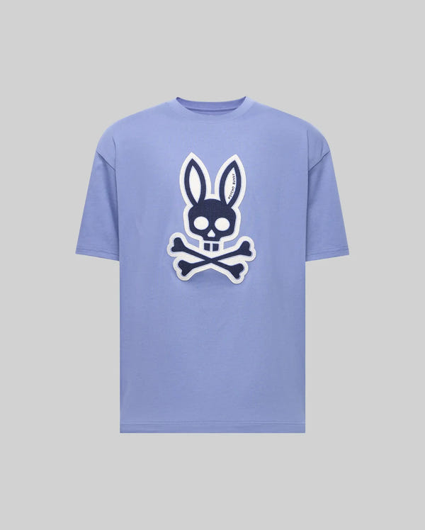 The Psycho Bunny MENS RYDER OVERSIZED FIT TEE (MT0200062) is a light purple premium tee with a bold black and white bunny skull and crossbones graphic on the front, shown against a plain gray background.