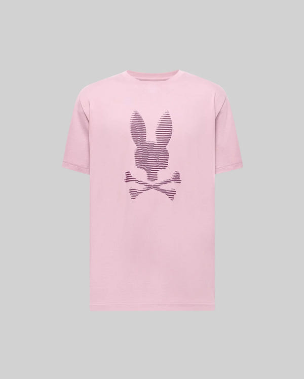 The Psycho Bunny MENS GRANT BUNNY GRAPHIC TEE (MT0200081) is a light pink Pima cotton tee featuring a dark purple outlined bunny head above crossed bones, showcased on a plain gray background.