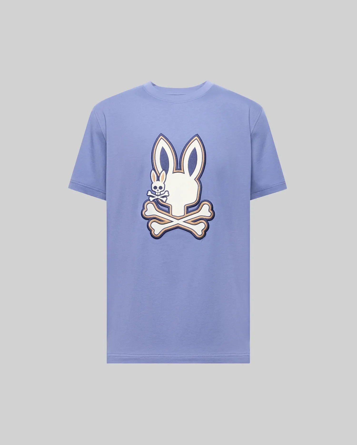 The Psycho Bunny MENS WADE GRAPHIC TEE (MT0200106) is a light purple 100% cotton shirt featuring a large white cartoon bunny head with crossbones on the front.