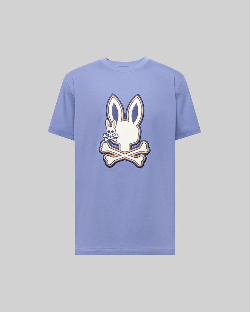The Psycho Bunny MENS WADE GRAPHIC TEE (MT0200106) is a light purple 100% cotton shirt featuring a large white cartoon bunny head with crossbones on the front.