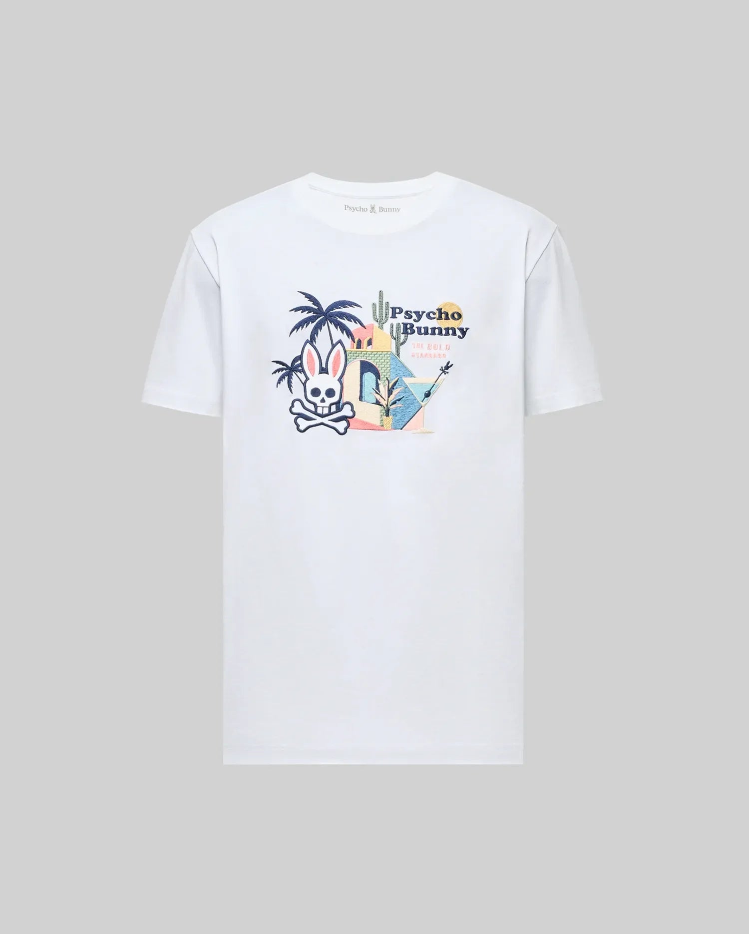 The Psycho Bunny MENS SHANE GRAPHIC TEE (MT0200175) is a white Pima cotton T-shirt with an embroidered cartoon bunny, crossbones, palm trees, cacti, and "Psycho Bunny" text on the back—ideal for summer style.