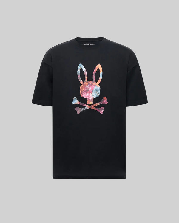 The Psycho Bunny MENS NOVAN GRAPHIC TEE - MT0200177 is a black Pima cotton shirt featuring a vibrant tie-dye style Printed Bunny with upright ears above crossed bones on the chest, set against a gray background.