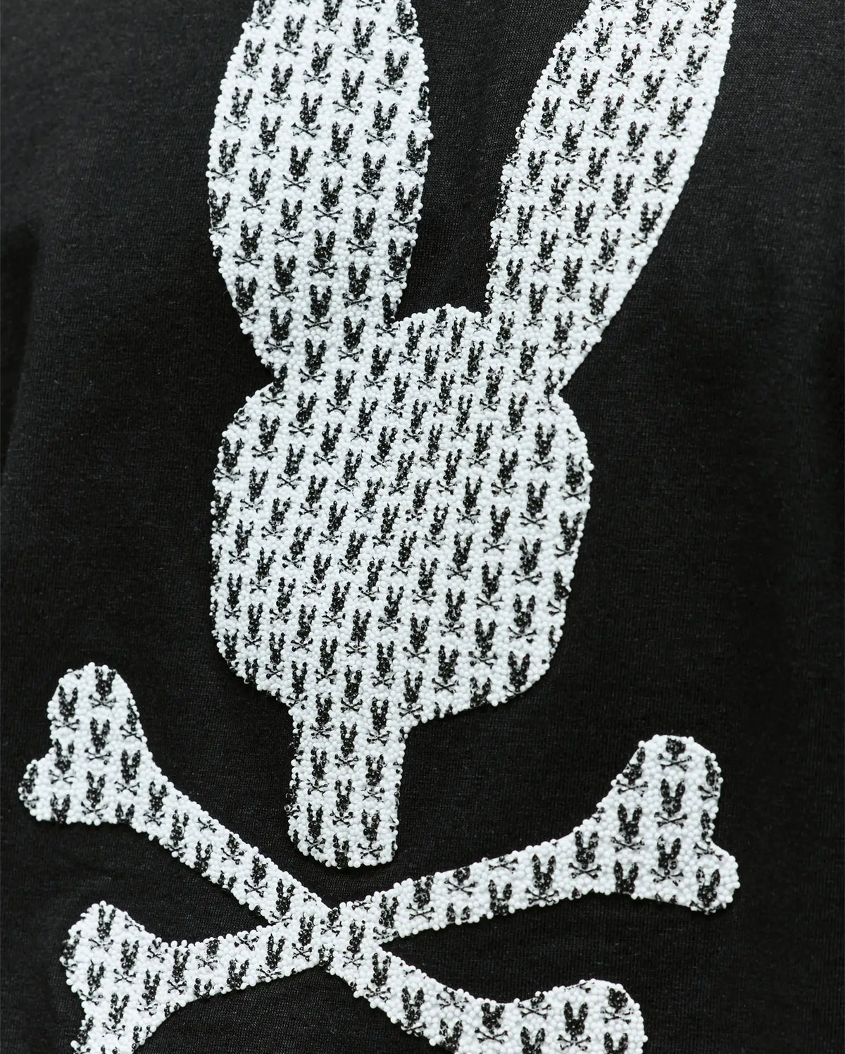 The Psycho Bunny MENS TALON GRAPHIC TEE (MT0200179) is a regular fit, 100% cotton black tee featuring a white Bunny skull and crossbones graphic with smaller rabbit icons.