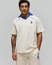 Mens Toby Jersey, a relaxed fit cream jersey polo with a royal blue V-neck collar, blue piping, and an embroidered Psycho Bunny logo on the left chest.