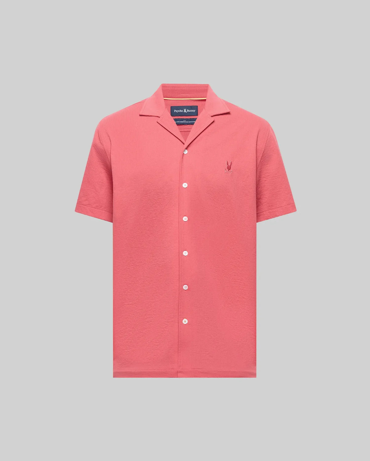 The PsychoBunny MENS JAYME KNIT SEERSUCKER CABANA COLLAR SHIRT (MT0300002) is a short-sleeved, button-up in coral pink with a cabana collar and embroidered logo, crafted from a premium cotton blend and shown on a light grey background.