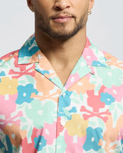 A person wears the Psycho Bunny MENS MEYLON STRETCH POPLIN SHIRT - MT0300034, featuring a colorful floral pattern. Only the lower half of their face and upper torso are visible.