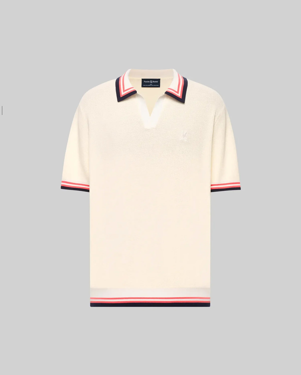 The Psycho Bunny MENS CARTER JOHNNY COLLAR KNIT POLO (MT0400093) is a cream, 100% cotton short-sleeve polo with a deep V-neck Johnny collar and red/navy colorblocked stripes on the collar, sleeves, and hem, shown on a light gray background.