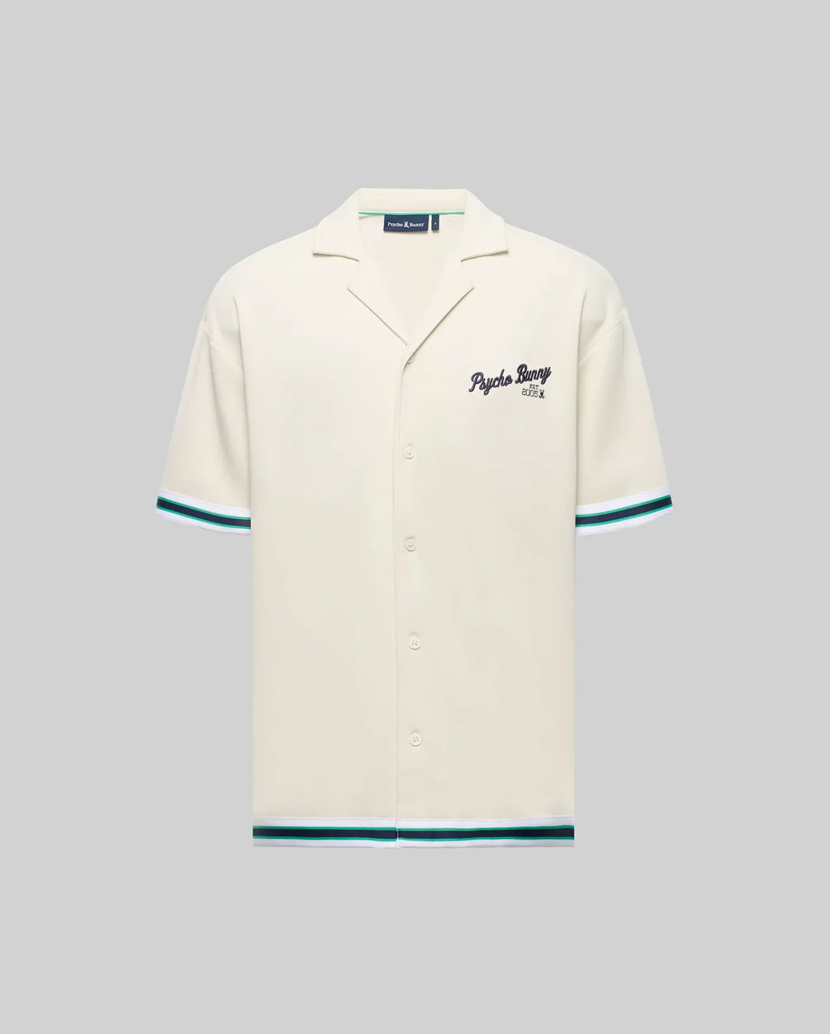 The Psycho Bunny MENS BASIL TAPED CAMP COLLAR SHIRT (MT0500004) is a cream, short-sleeve shirt with a Johnny collar, teal and black striped sleeves and hem, embroidered "Psycho Bunny" on the chest, made from cotton-modal blend. Shown on gray.