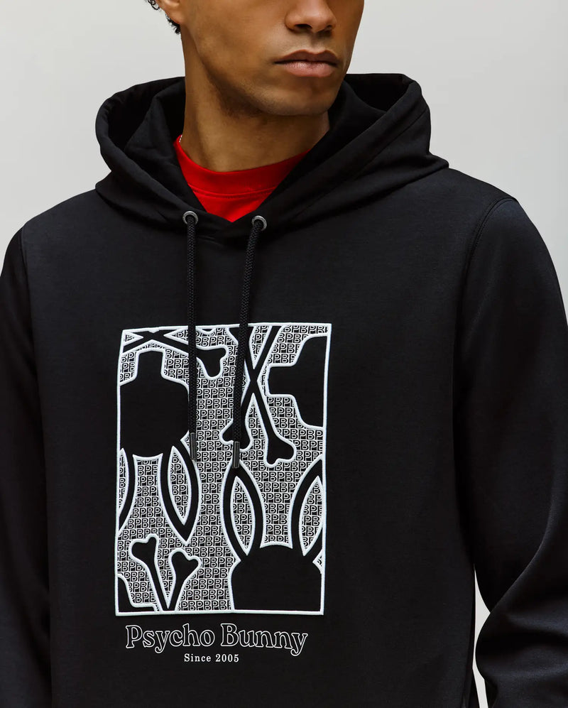 A person wearing the Psycho Bunny MENS GLENN HOODIE - MT0500008 in black, featuring a Bunny graphic and "Psycho Bunny Since 2005" text on the front. They are shown from the shoulders up, facing slightly to the side.
