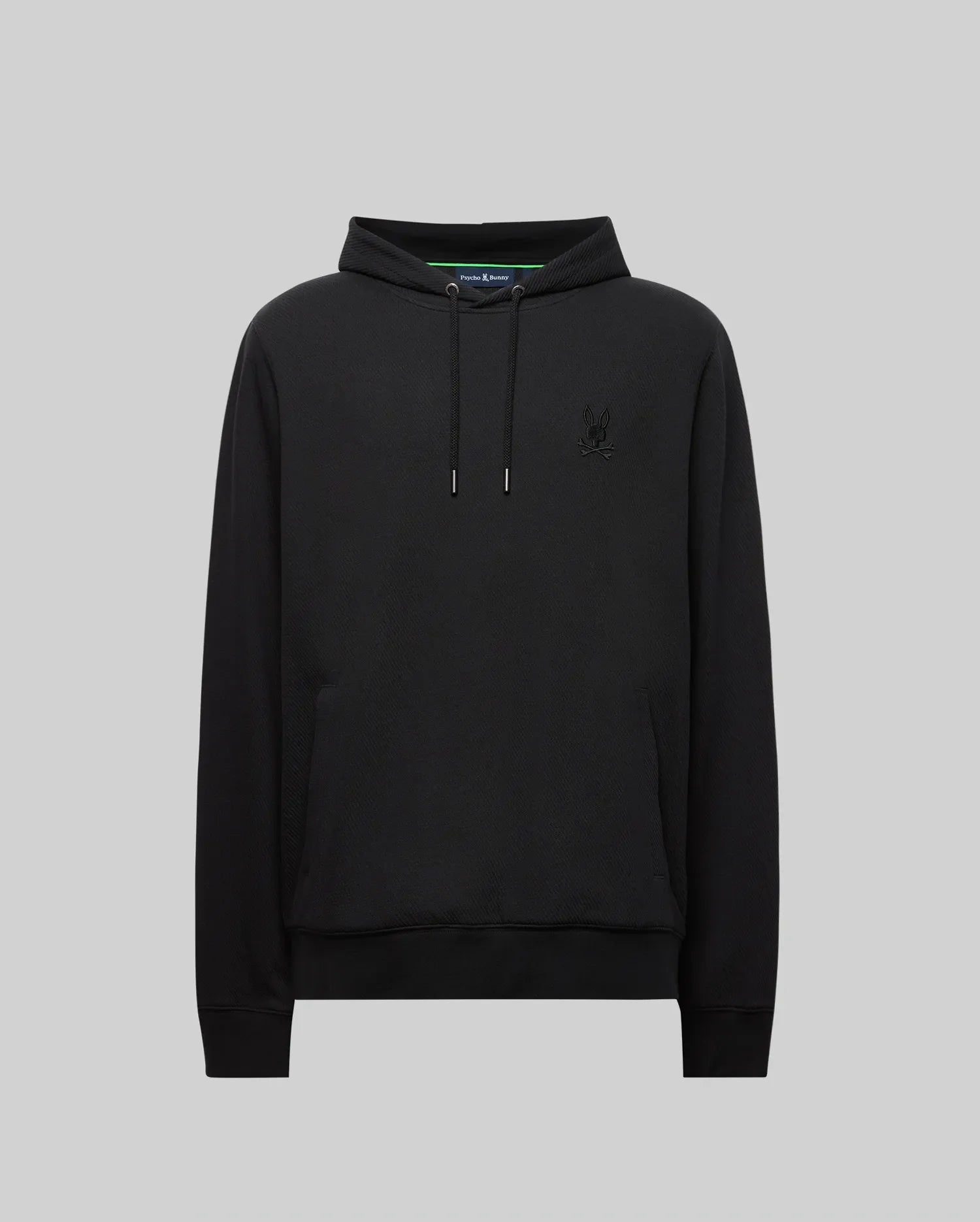 The Psycho Bunny MENS KAI HOODIE (MT0500019) in black features drawstrings, a front pocket, and a subtle embroidered Bunny logo on the left chest, shown against a plain gray background.